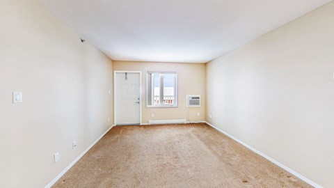 a spacious living room with white walls and carpet